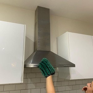 woman cleaning kitchen hood